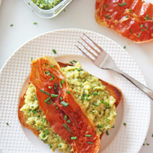 Green Eggs and Ham (Pesto Scrambled Eggs and Crispy Prosciutto) Recipe. Grab pesto, make the creamiest scrambles eggs, and grab a sheet pan for crispy sweet prosciutto. This is a fast treat yourself brunch, breakfast for dinner, or birthday recipe! Happy Cooking! www.ChopHappy.com #scrambled eggs #breakfastrecipe