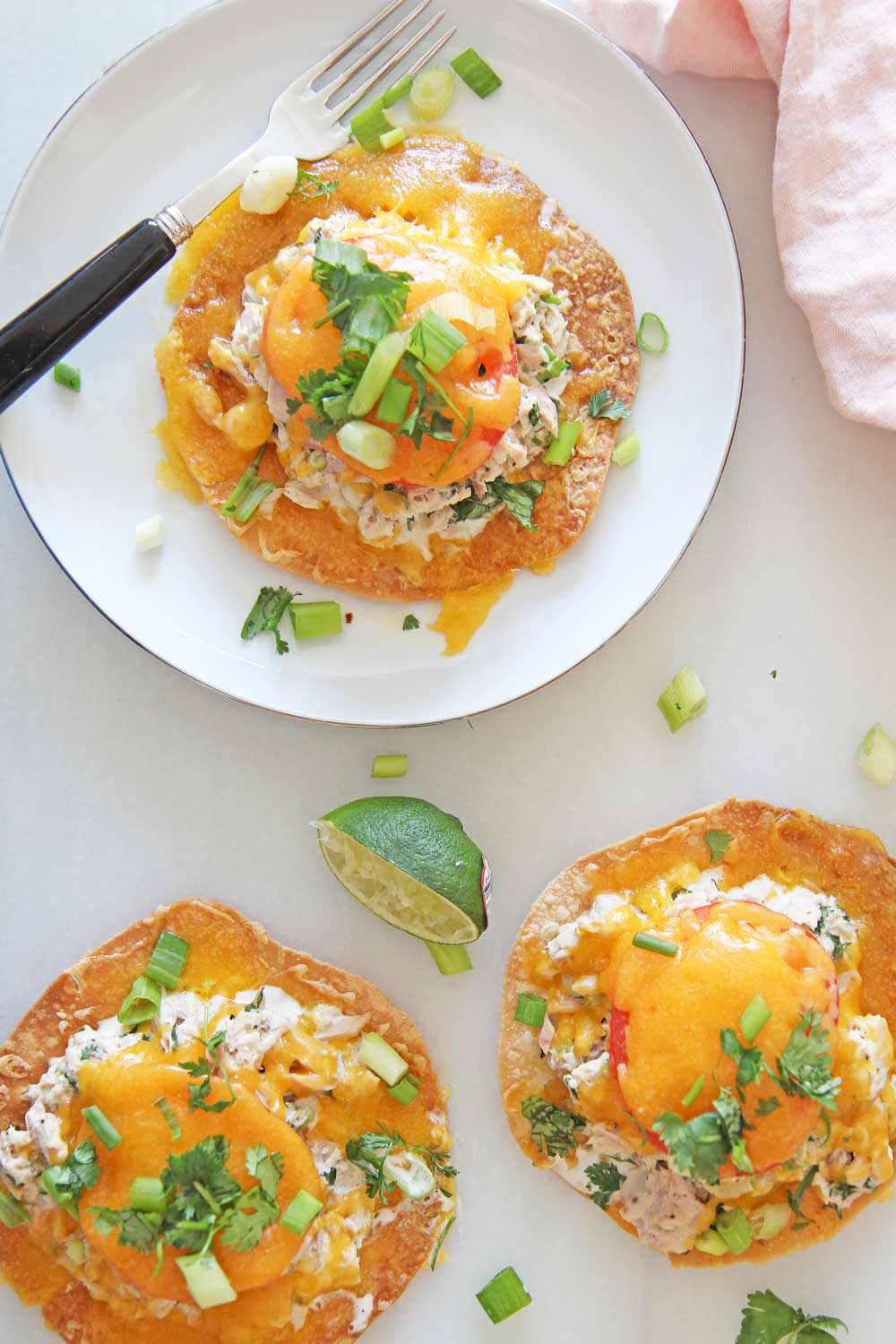 Tuna Melt Tostadas are so easy to make and are the perfect pantry dinner. Grab tortillas, tuna, mayo, cilantro, scallions, cheese, and lime. Happy Dinner cooking! www.ChopHappy.com #tostada #tunamelt